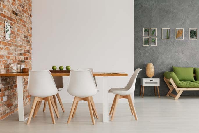Wooden dining table and chairs by an exposed brick wall in a bri
